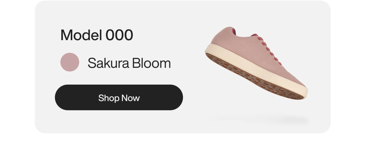 Light pink sneaker labeled 'Model 000 Sakura Bloom' floating against a white background. Includes a black 'Shop Now' button, conveying modern, sleek design.