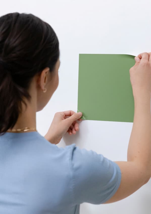 Woman applying Peel-and-Stick Swatch to wall