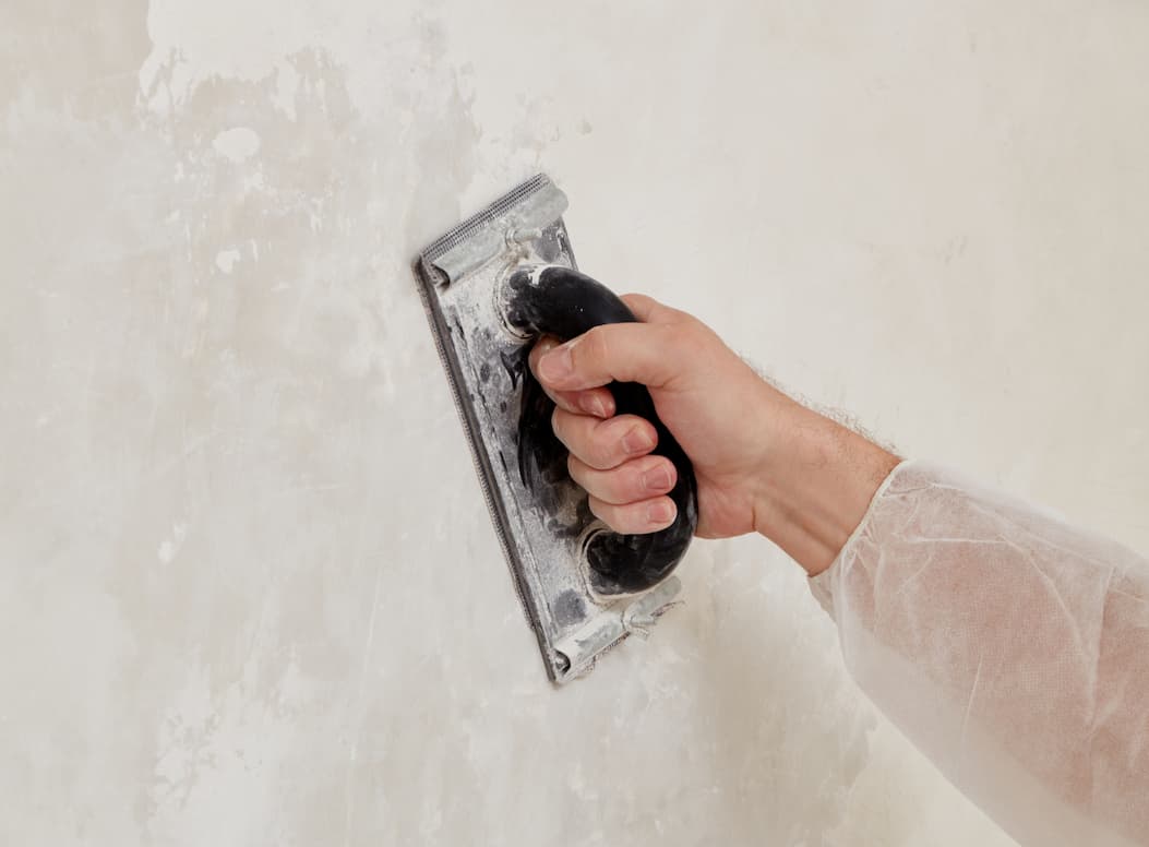 Person sanding the wall