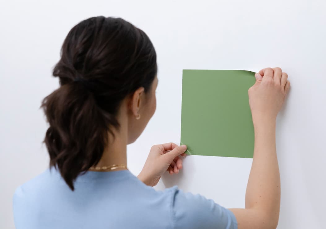 Woman applying Peel-and-Stick Swatch to wall