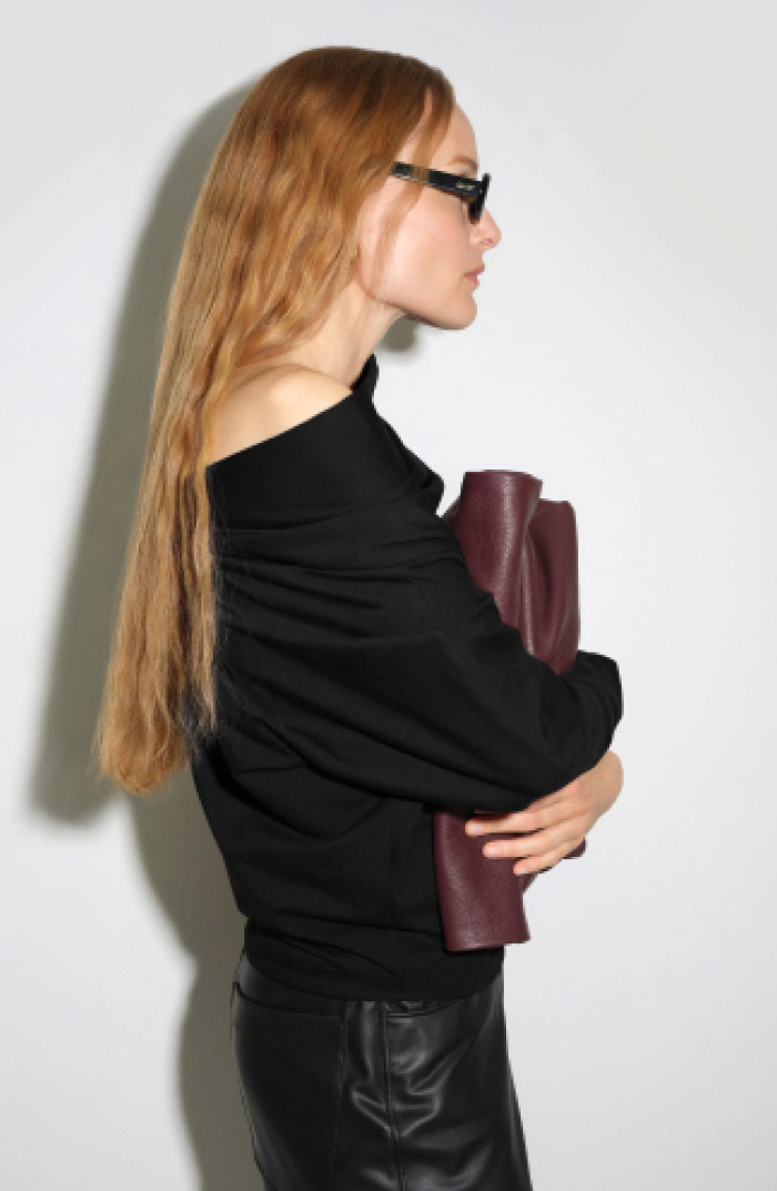 Nada in dark sunglasses wears a black Apex Top and black leather pants against a white backdrop.