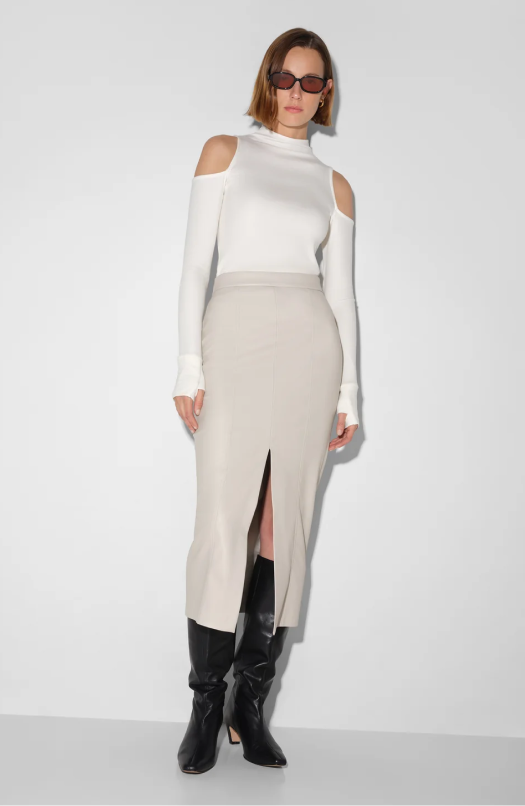 Mali wears a bone Nerida Skirt with a front slit, styled with Harmony Top and black knee-high boots.