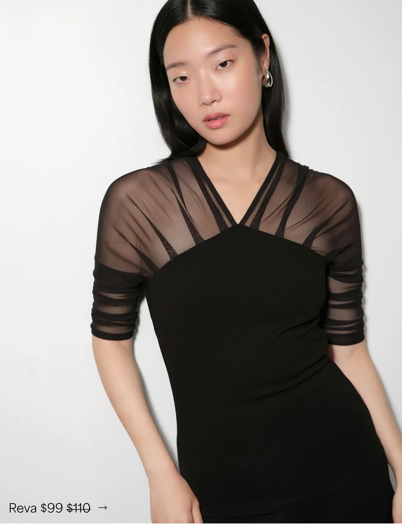 Xun wears a black Reva Top with sheer elbow-length sleeves and layered mesh neckline detailing, priced at $99, originally $110.