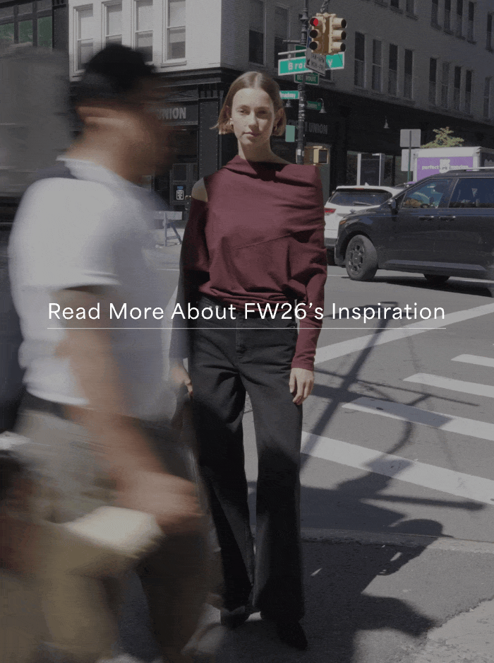 GIF shows Mali stands at a city crosswalk wearing a burgundy cutout long-sleeve Apex Top with black wide-leg pants and carrying a dark tote, with the text “Read More About FW26’s Inspiration.”