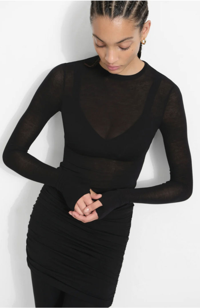 Aliza wears a sheer black Mara Top with a ruched black Jayne Skirted Leggings, shown in a full-length view alongside a close-up of the gathered skirt detail.