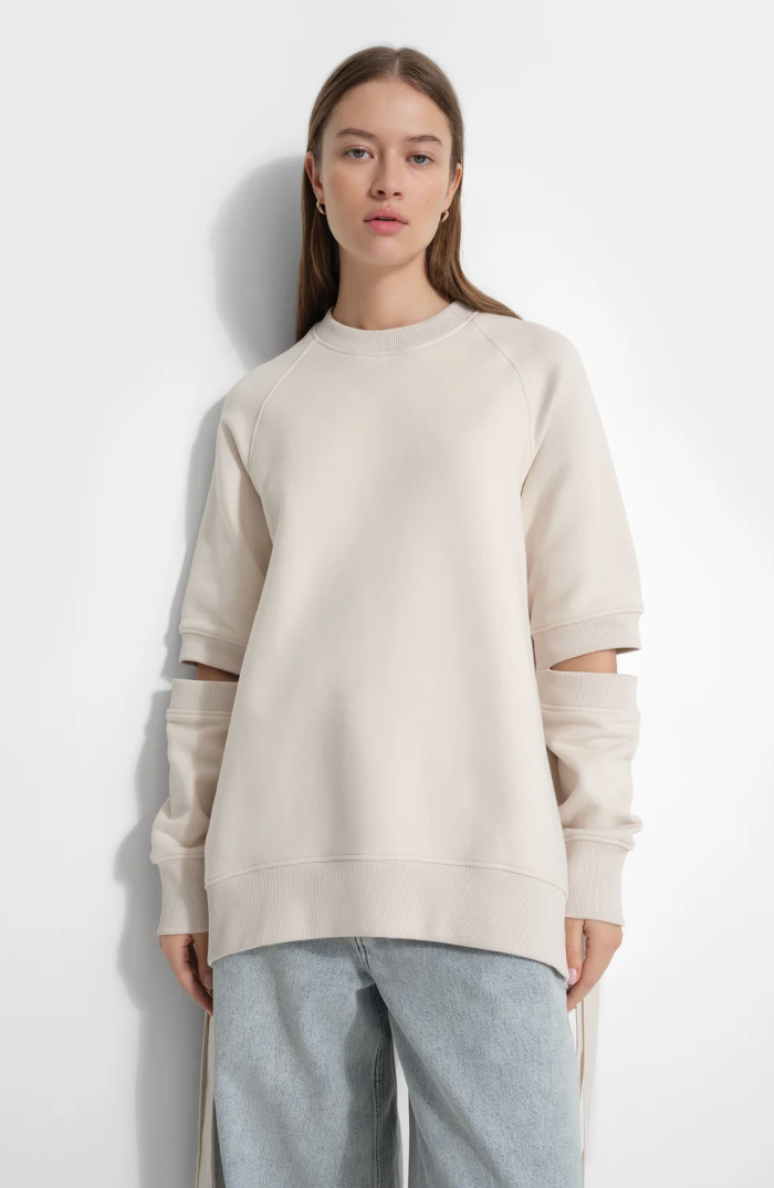Bianca wears a cream Mavi Sweatshirt with detachable-style long sleeves and light-wash jeans against a white backdrop.