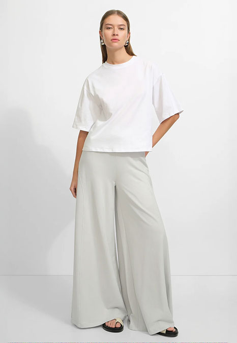 Bianca wears a crisp white Degraw Tee with flowing wide-leg mist Hylan Pants