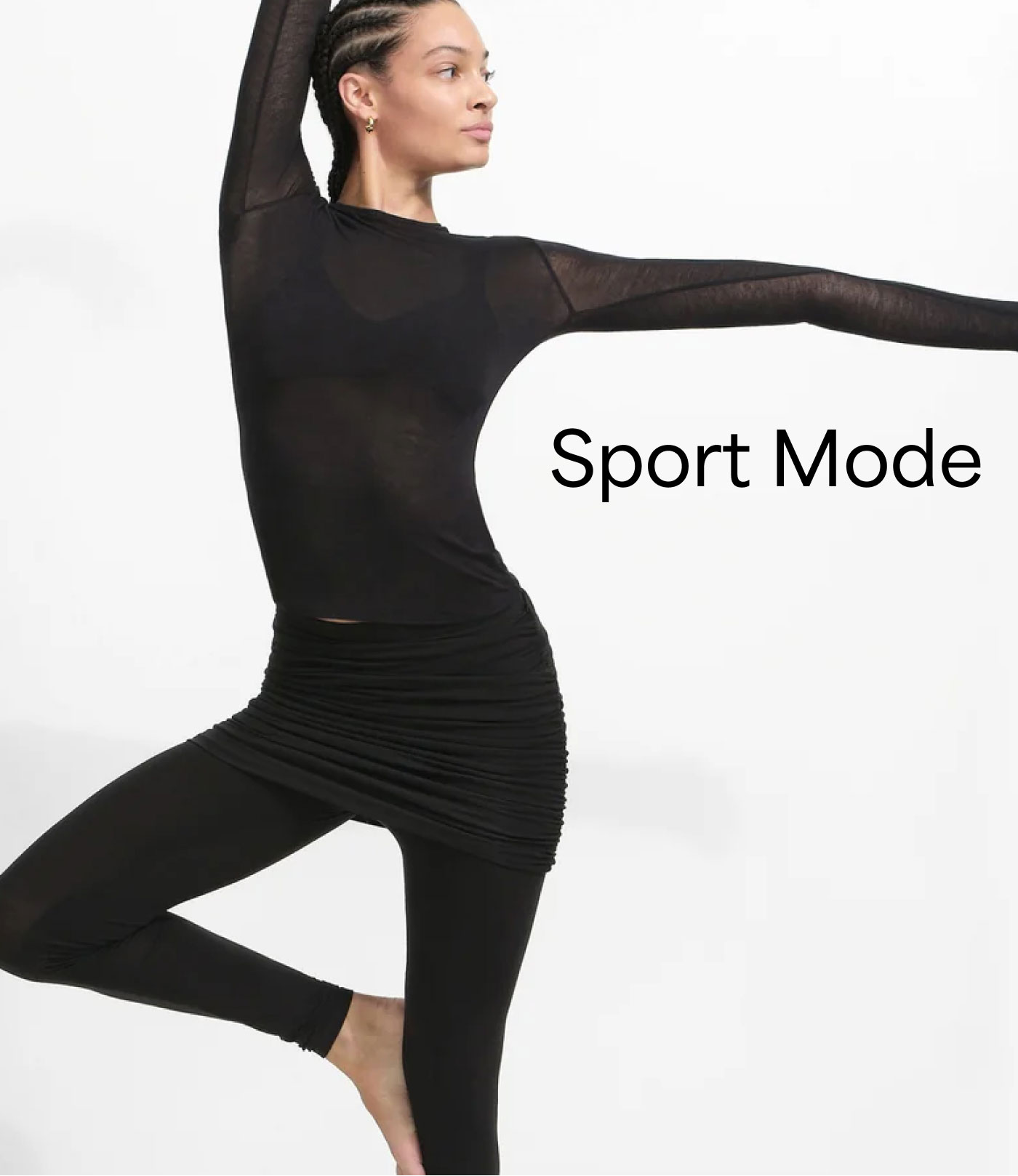 Aliza holds a yoga-inspired balance pose in an all-black look with The Mara Top and The Jayne Skirted Leggings, alongside the text “Sport Mode.”