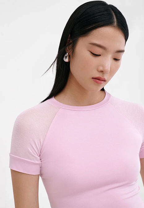 Xun wears a fitted pink Harling Tee with sheer raglan sleeves, shown in a close-up against a white background.