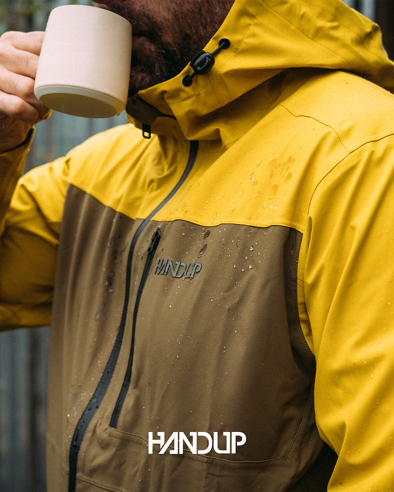 A man is fishing in a flannel that doubles as a jacket, on a fall day. 