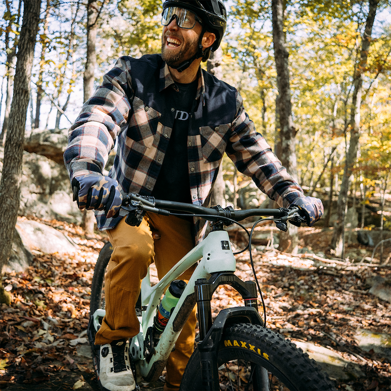 A bike rider smiles on a trail as he sits on his mountain bike. 