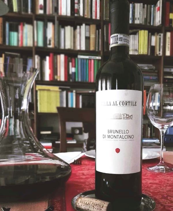 Bottle and carafe of Brunello Di Montalcino DOCG 2015 by Villa Al Cortile on a table in a library.