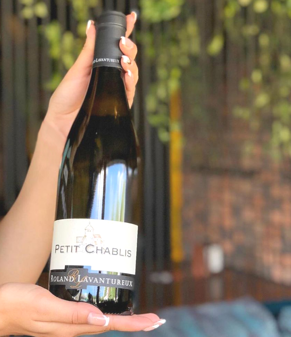 Bottle of Petit Chablis 2019 by Roland Lavantureux held in a woman's hand showing the label.