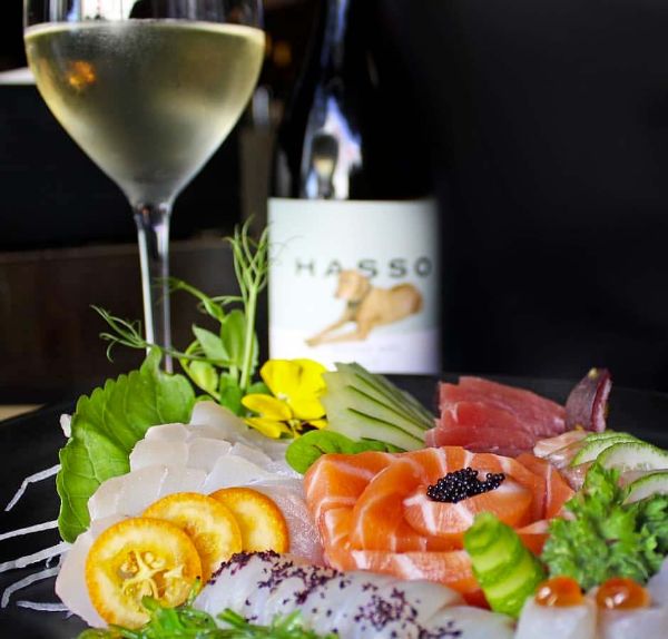 Bottle and glass of Hasso White Douro DOC by Kranemann 2018 by a plate with a beautiful arrangement of fish.