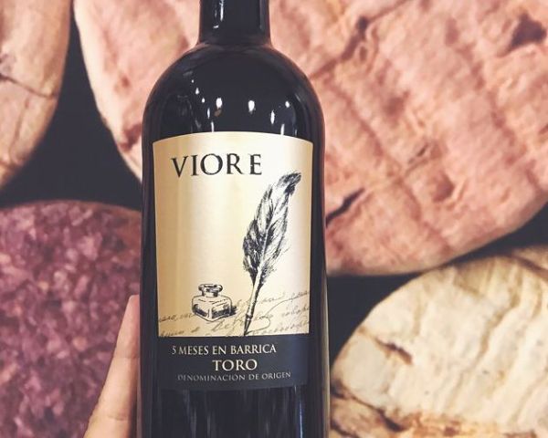 Bottle of Viore Toro 5 Mesas 2019 by Bodegas Riojanas in front of several loaves of bread.