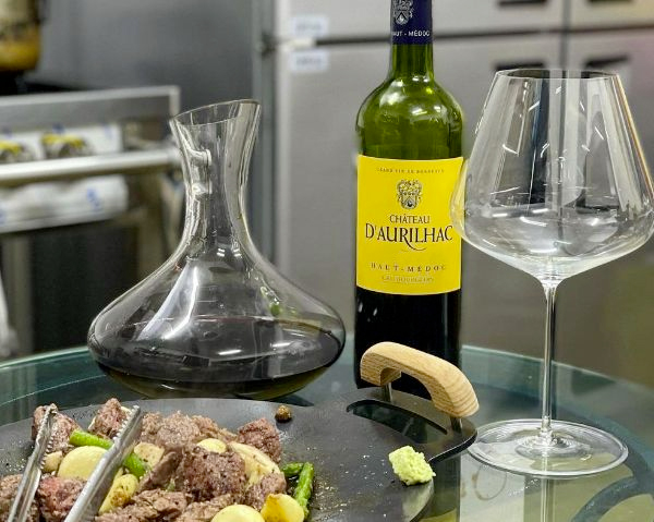 Bottle of Haut-Medoc 2011 by Chateau d'Aurilhac on table with glass and carafe.