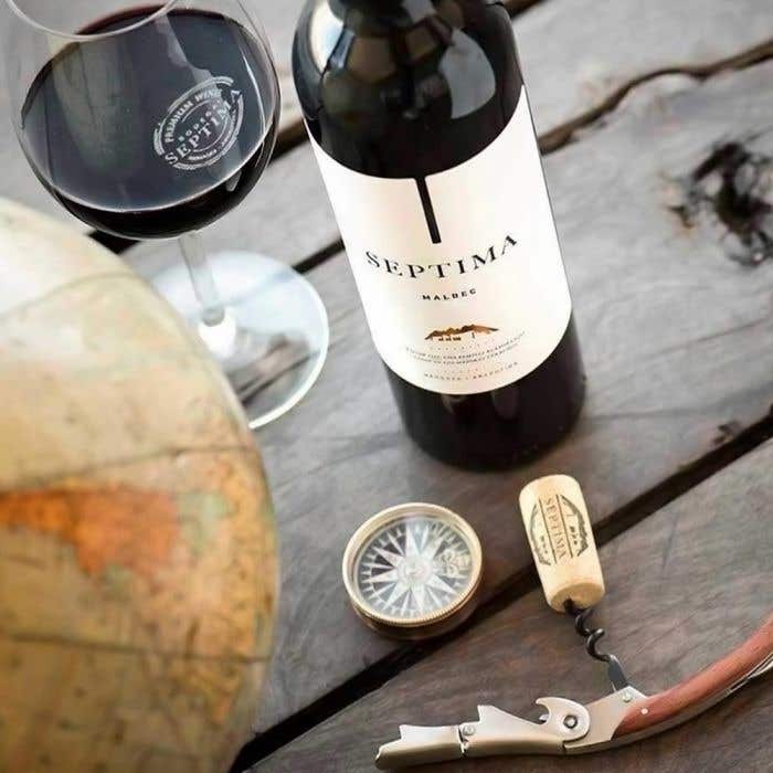 Bottle and glass of Bodega Septima Malbec 2020 on a wooden table.