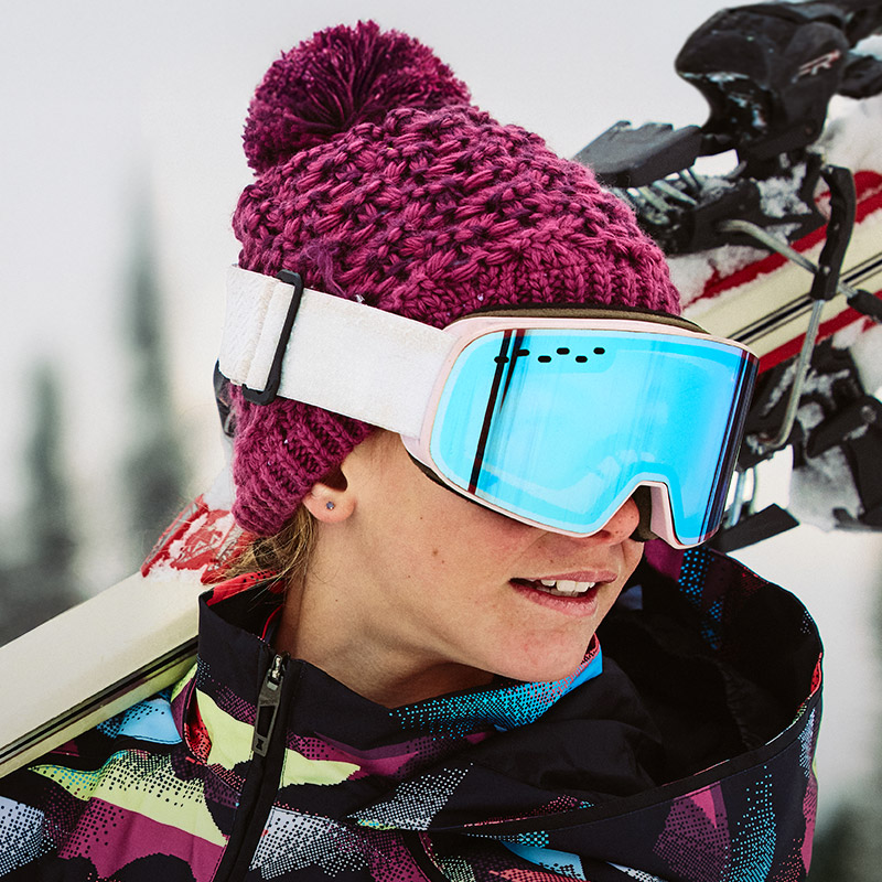 Girl skier wearing an acai color beanie and ski jacket with acai color accents.