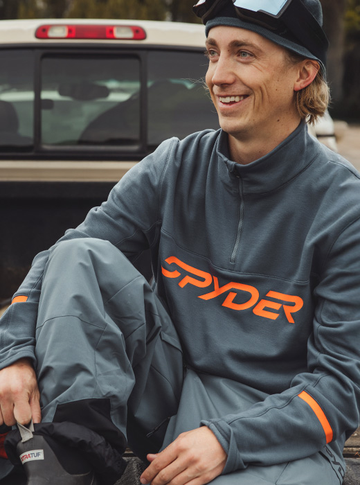 Skier sitting in the back of a trucking wearing Speed Fleece Half Zip