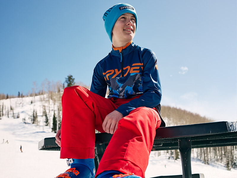 Boy sitting on bench wearing ski pants