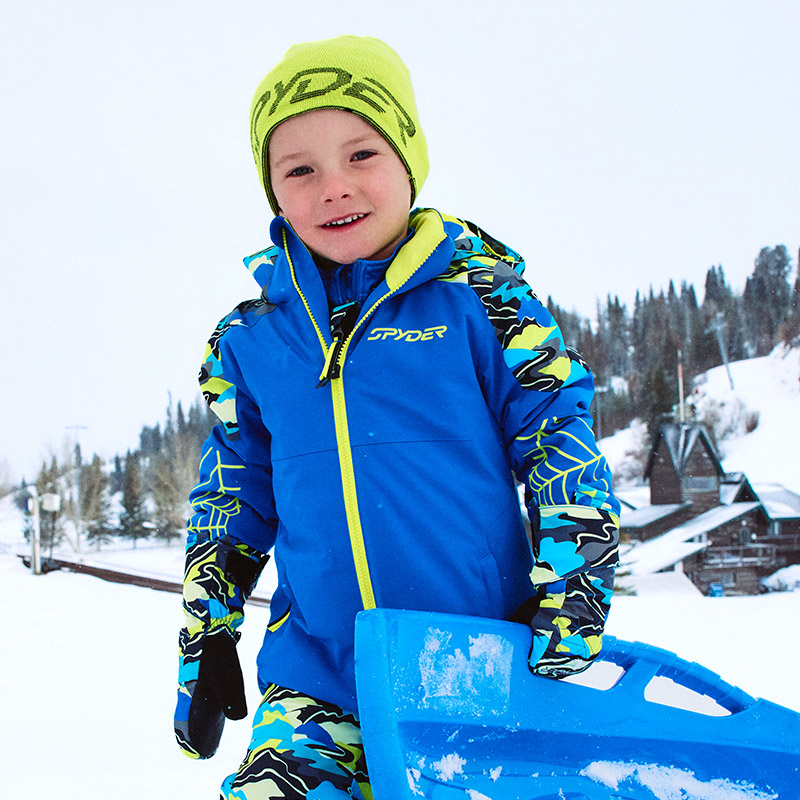 Boy in a cobalt blue jacket with lime accents playing in the snow.