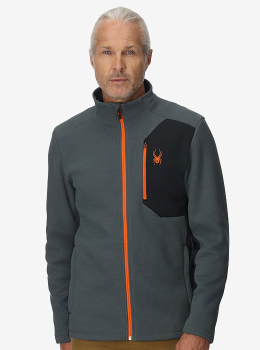 Man in a grey full zip fleece featuring an orange logo and zipper.