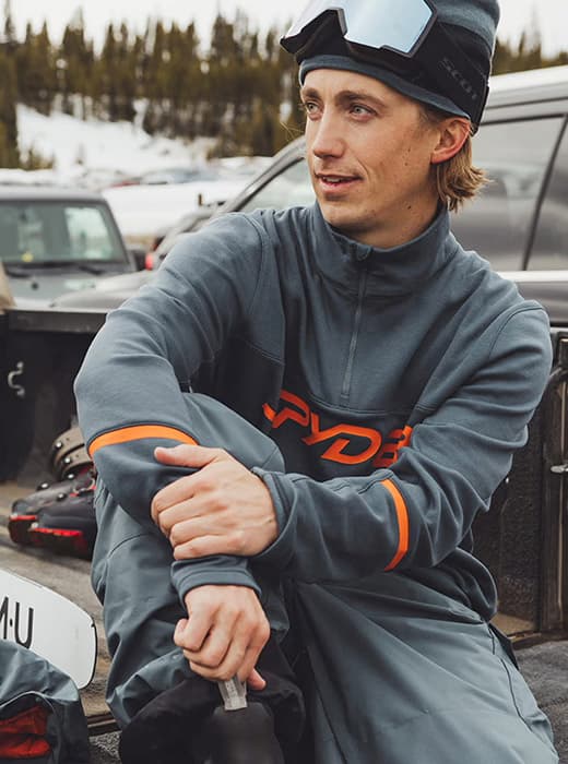 Image of a man wearing slate blue and orange quarter zip jacket.