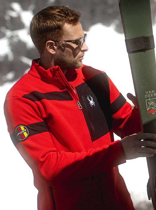 Skier wearing a textured red light jacket, looking at skis