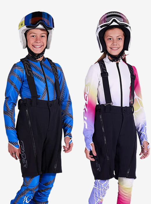 Two ski kids, a boy and girl, wearing training shorts on a grey background