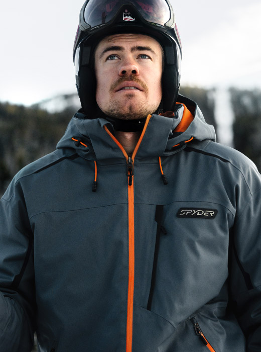 Male skier wearing a slate blue ski jacket with orange accents.