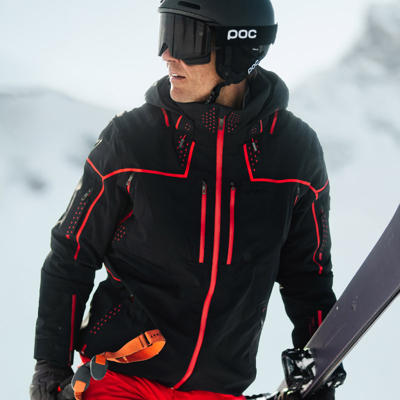Skier wearing the technical black with red accents Pinnacle Jacket