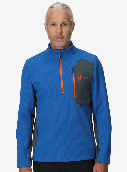 Man in a blue quarter-zip pullover featuring an orange logo and zipper.
