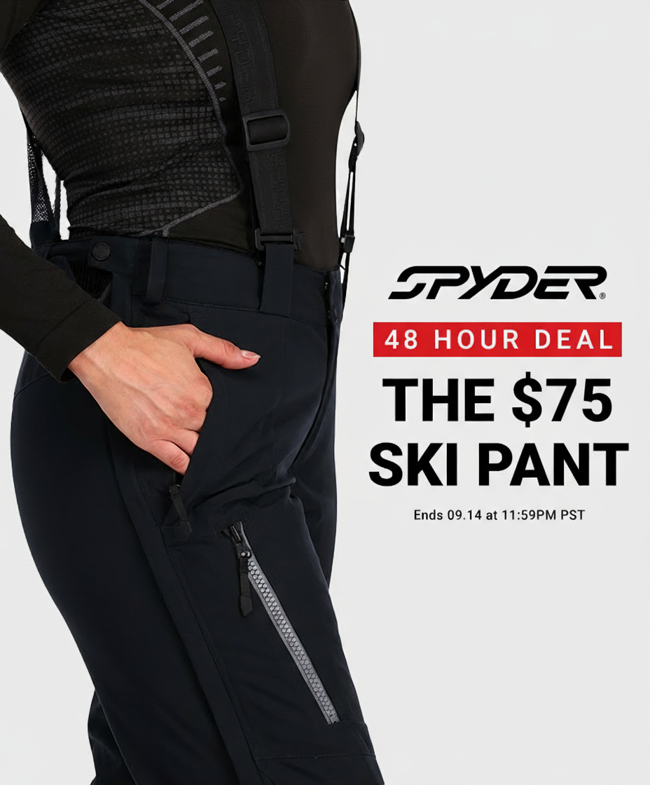 Woman wearing a Spyder ski pant showing the full leg zip feature on a light grey background