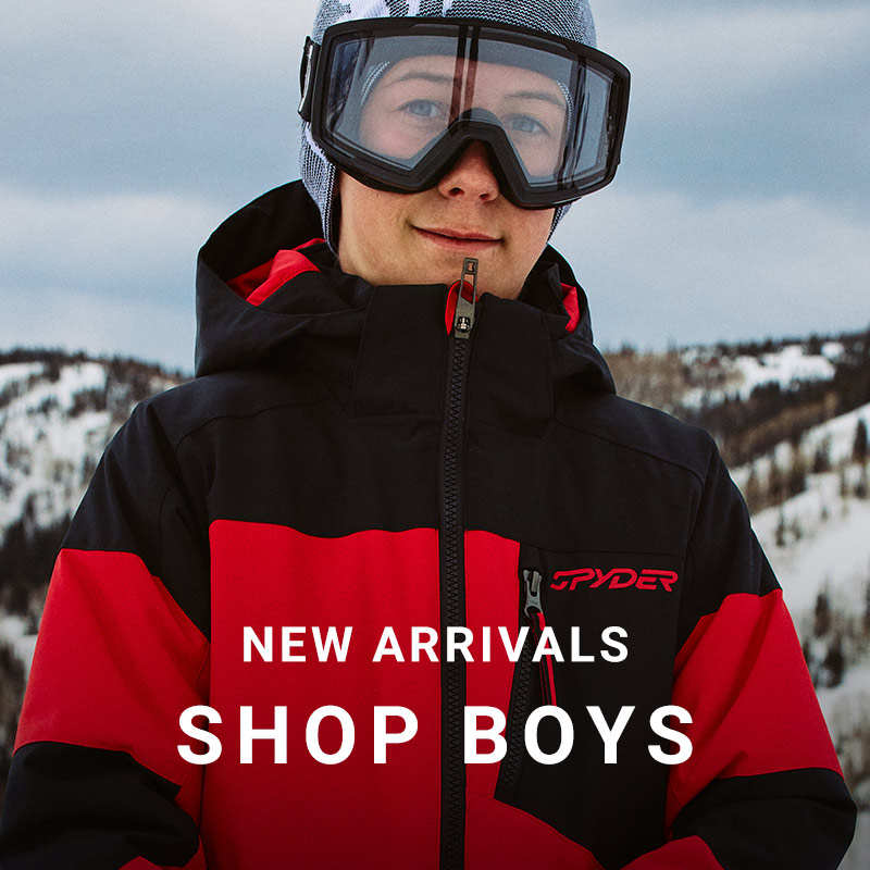 Boy standing in a snow mountain scene with clear goggles wearing a black and red Spyder ski jacket. Message: New Arrivals Shop Boys.