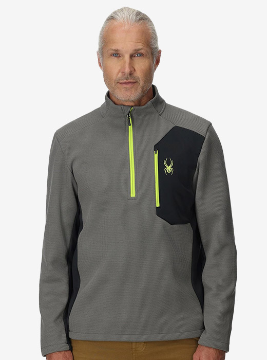 Man in studio wearing a half zip light jacket in grey and black with lime accents.