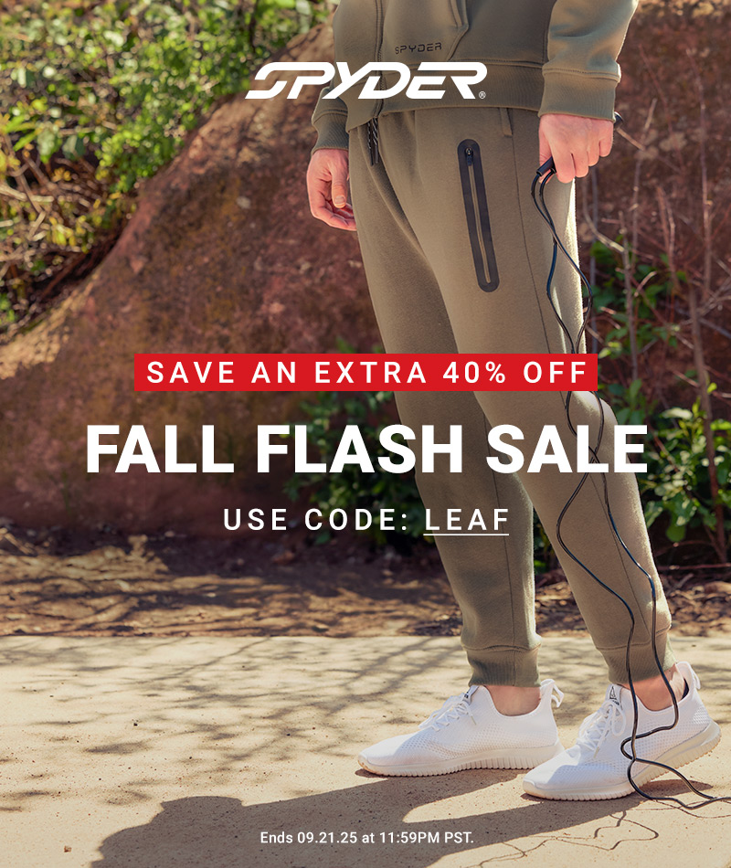Photo of a male model from the waist down holding a jump rope wearing a full jogger suit set against a rock and brush backdrop.
