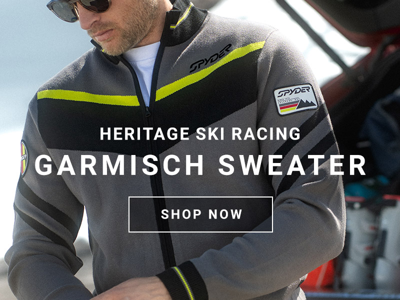 A person wears a gray Spyder sweater with yellow accents, promoting the Heritage Ski Racing Garmisch Sweater.