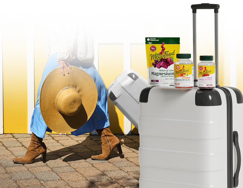 Woman pulling white luggage on a cobblestone road. | Luggage with Magnesium Soft Chews, Vitamin D3 & K2 Gummies, and Women's Pre+Pro Gummies