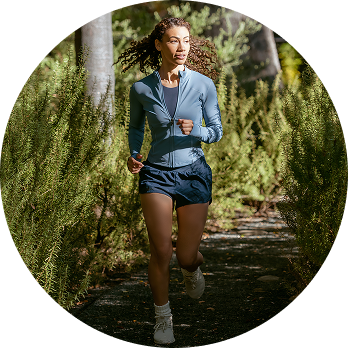 Woman running outside on a path lined with trees