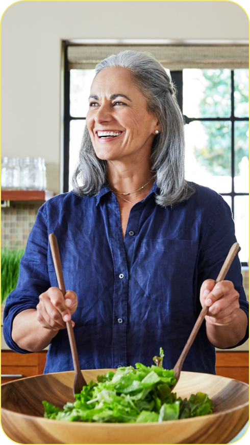 Woman making a salad in a wooden bowl in the kitchen