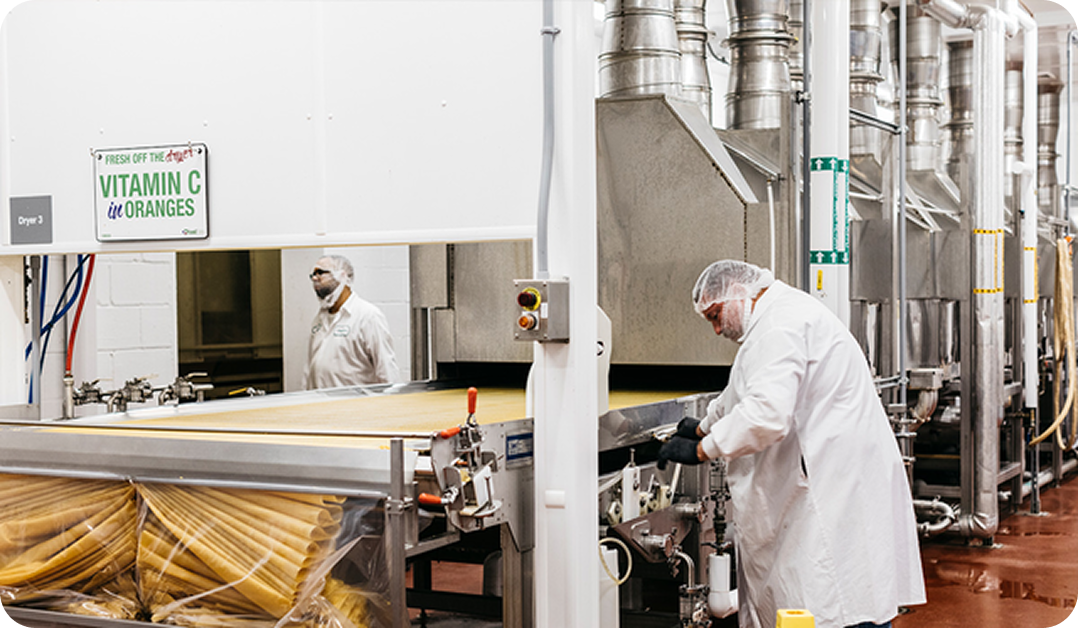 Production line with a man wearing a white lab coat and PPE