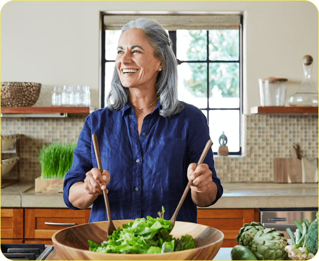 Woman making a salad in a wooden bowl in the kitchen