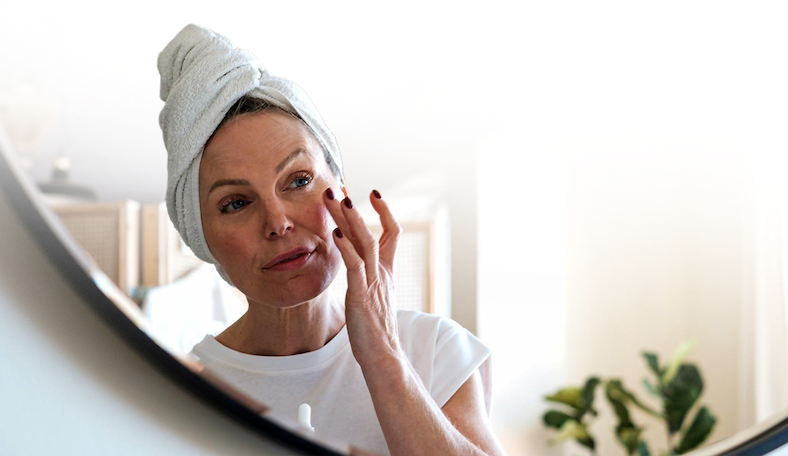 Woman with a towel on her hair getting ready in front of a mirror