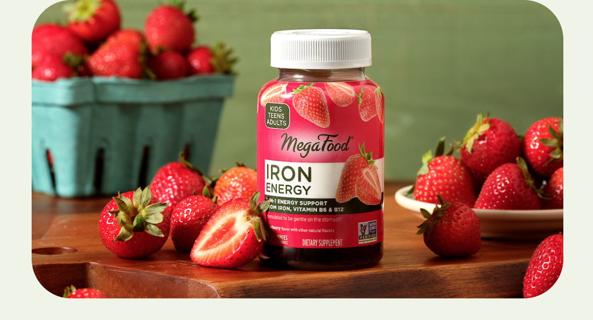 MegaFood iron energy gummies on a table next to fresh strawberries