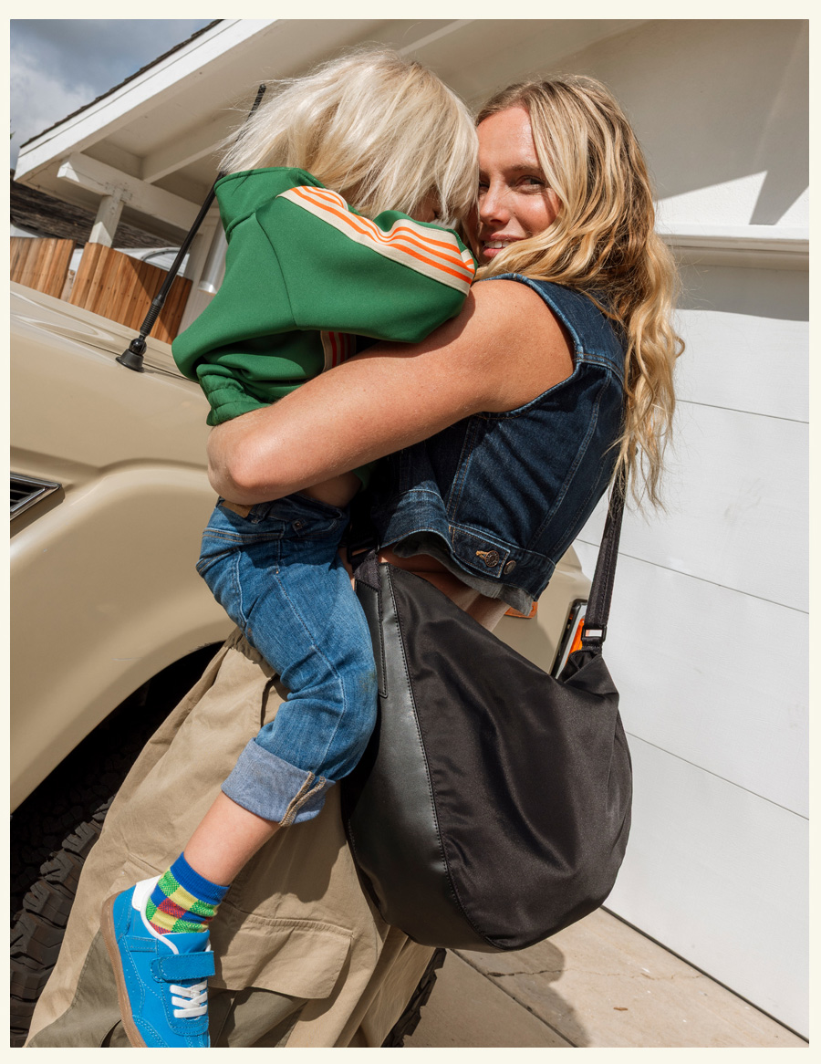 Mom holding baby wearing luna crossbody black