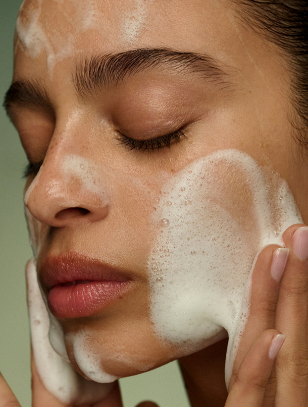 An image of a model washing her face with the new Tatcha Matcha Foam Cleanse, showcasing the foaming effect.