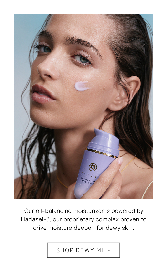 An image of a model posing with the Dewy Milk Moisturizer, Tatcha's oil-balancing moisturizer powered by Hadasei-3 a proprietary complex for dewy skin.