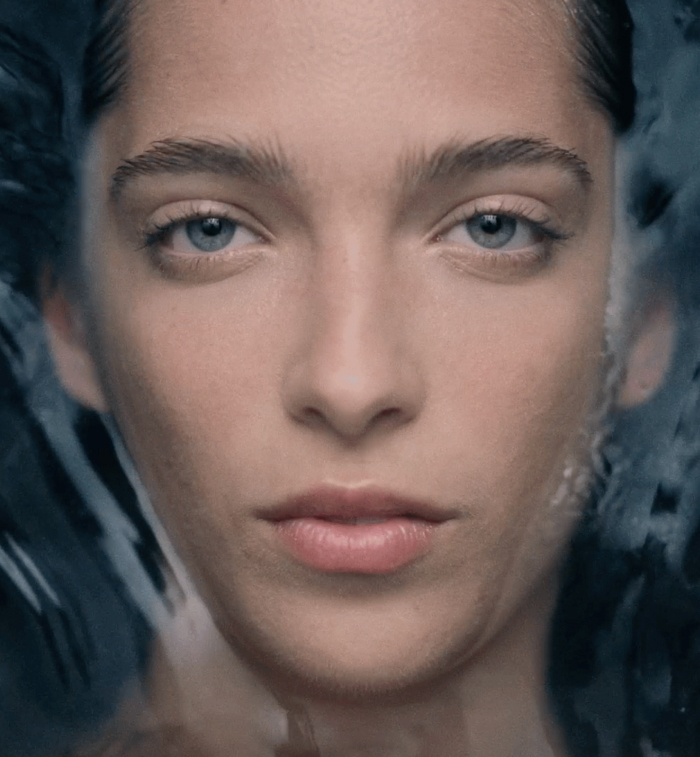 An image of a model's face with water in the background