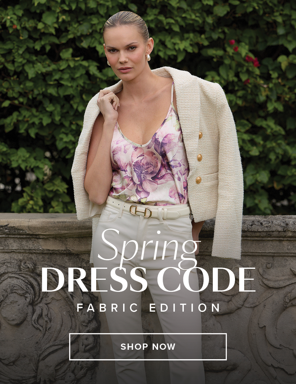 Spring Dress Code Fabric Edition. An image of a model posed in front of a stone ledge and a lush hedge behind her wearing a full look from our new Spring collection.