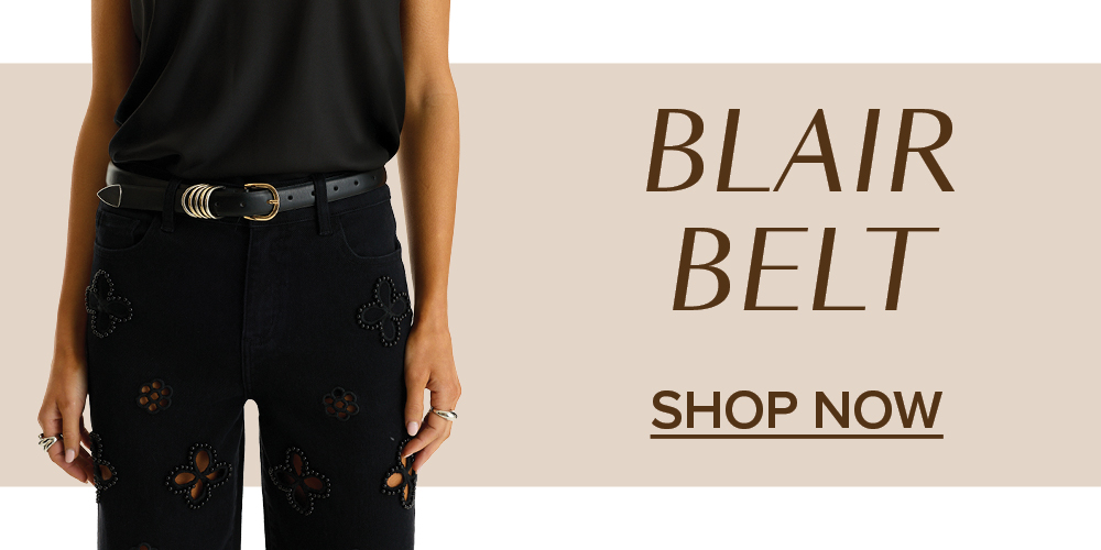 Blair Belt. Shop Now. A model stands to the left behind a beige background wearing the Black Blair Belt.